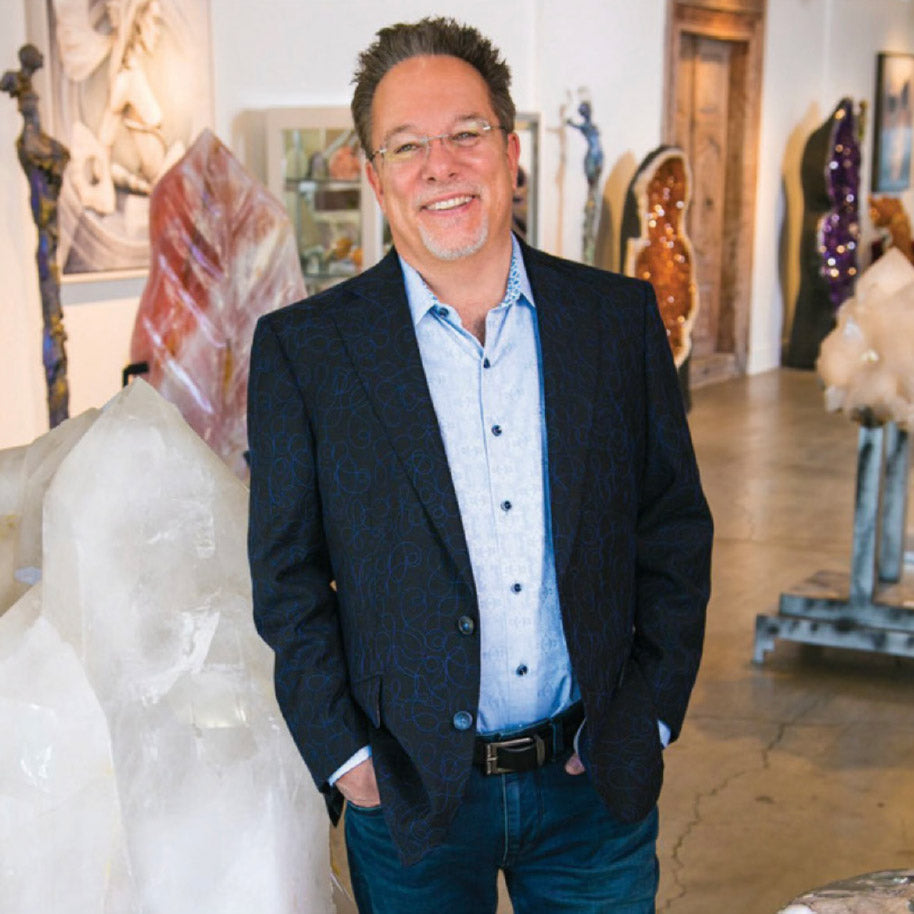 Mystic Journey Crystals founder Jeffrey Segal stands beside a large rose quartz inside our crystal gallery